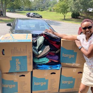 A photo of a woman standing with a lot of boxes packed with backpacks